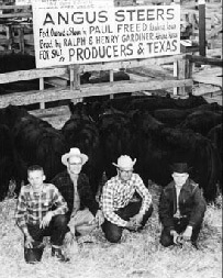Four gentlemen smiling and kneeling in front of their steers in this 1960 black and white photo.